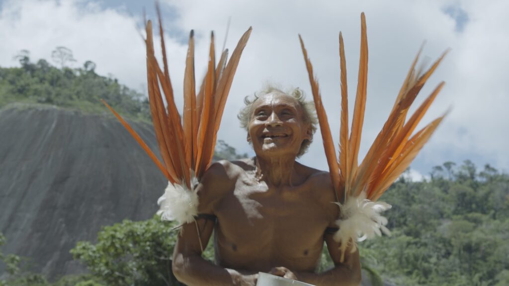 a Yanomami man holding orange feathers