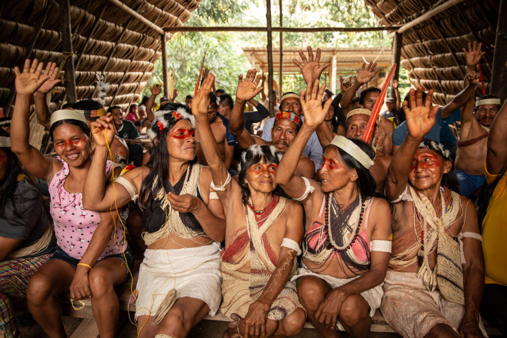 Waorani women raise their arms in the Ecuadorian Amazon