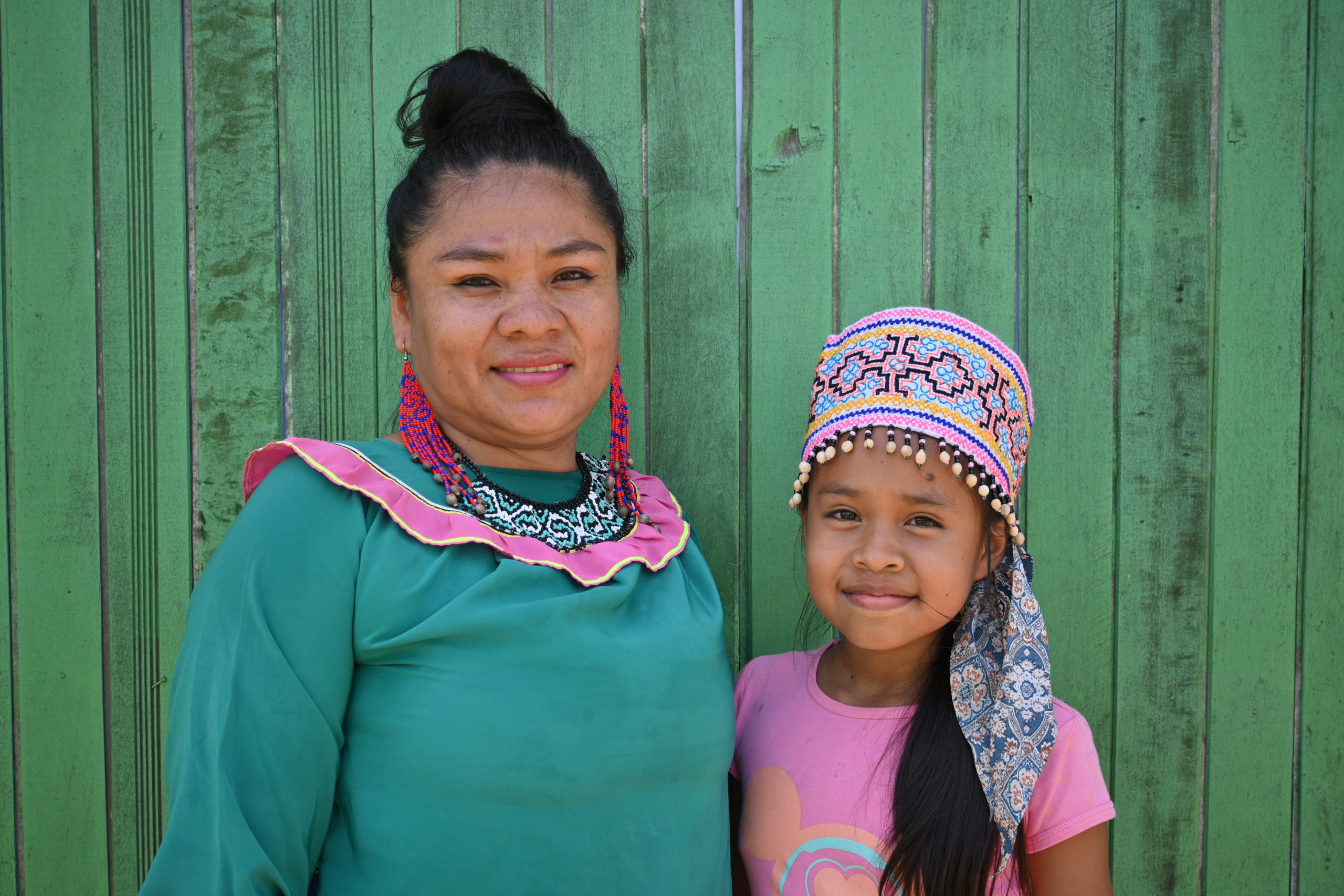 Forest Patrol Instructor Mirian Sanchez poses with her daughter, Abigail, in front of a green wall.