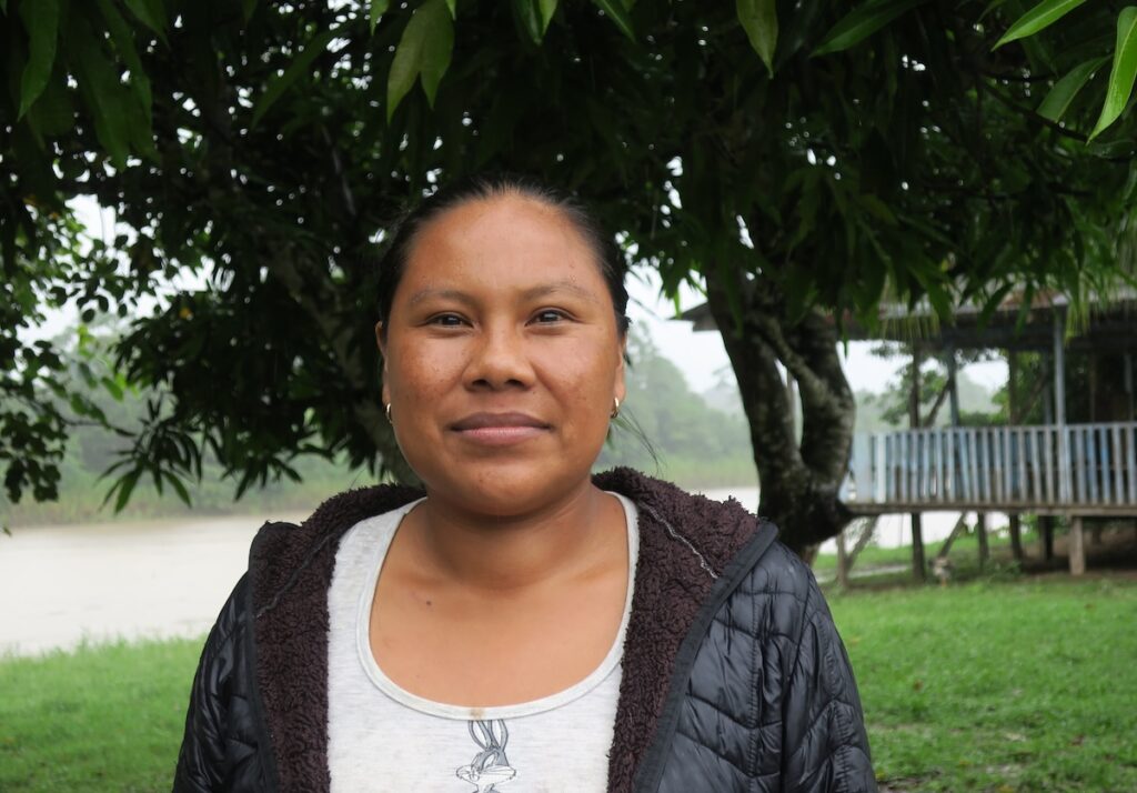 Beria Tamna Macedo smiles at the camera on a rainy day in her community in Peru's Amazon River Basin