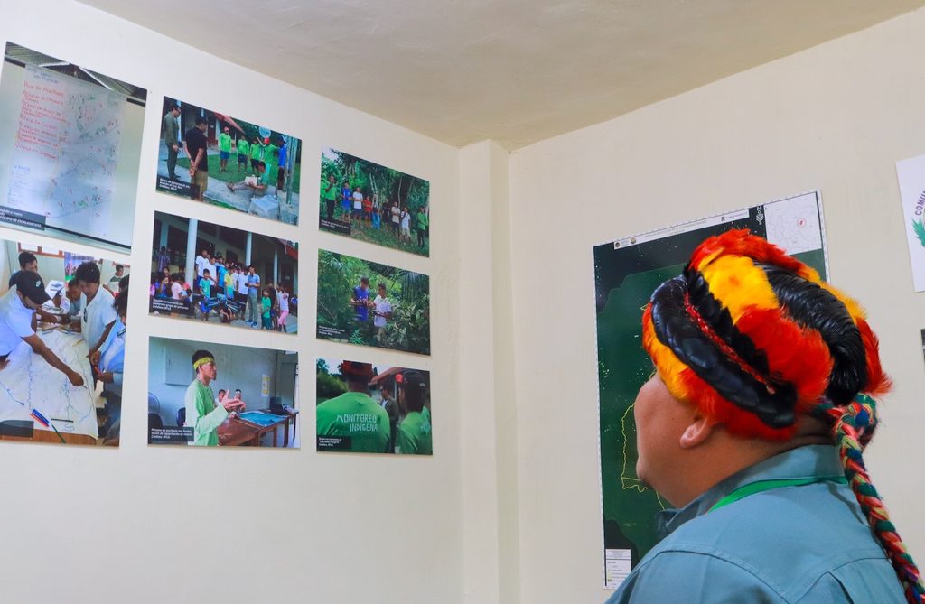 Fall 2026 Newsletter 4 A Shuar Indigenous leader contemplates photos of forest monitors at the Matsés monitoring hub