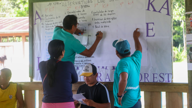 Indigenous leaders and RFUS staff at a town hall meeting in San Juan de Miraflores, Peru, explain options for solar power generations that the community could buy with money earned through the Rainforest Alert forest defense program