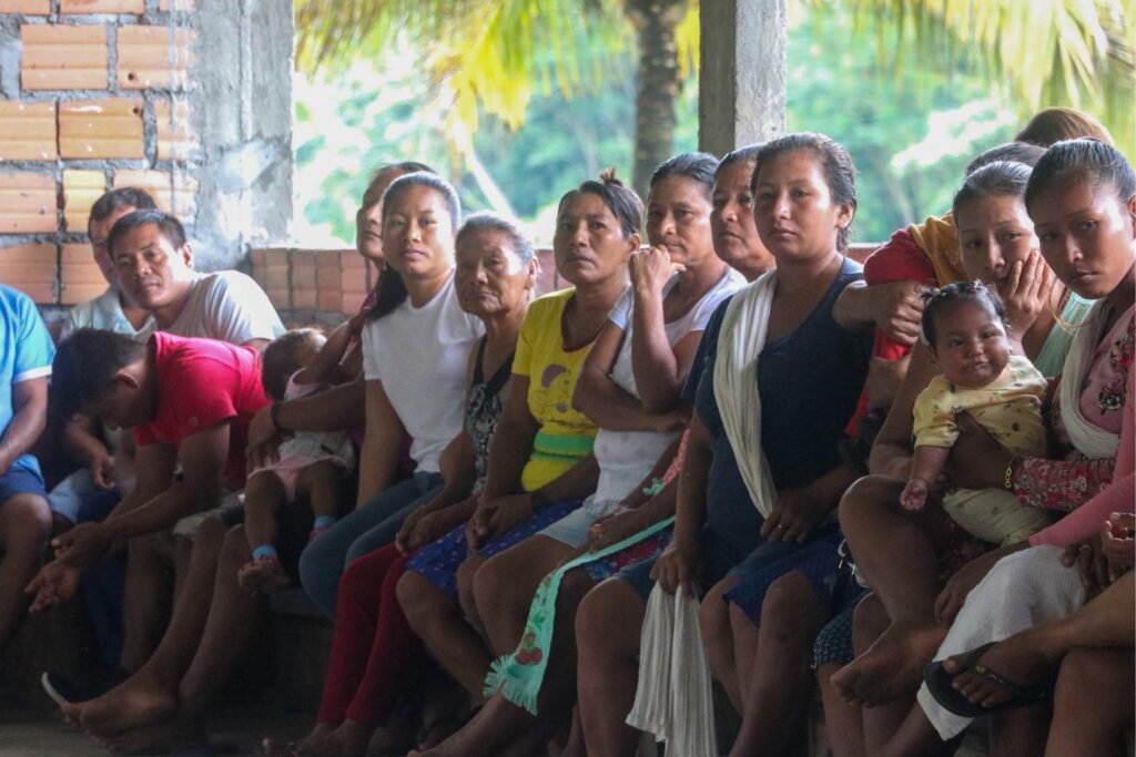 Members of a Kichwa Indigenous community engaged in a meeting, with women of all ages listening attentively, a representation of social cohesion and the active participation in communal decision-making.