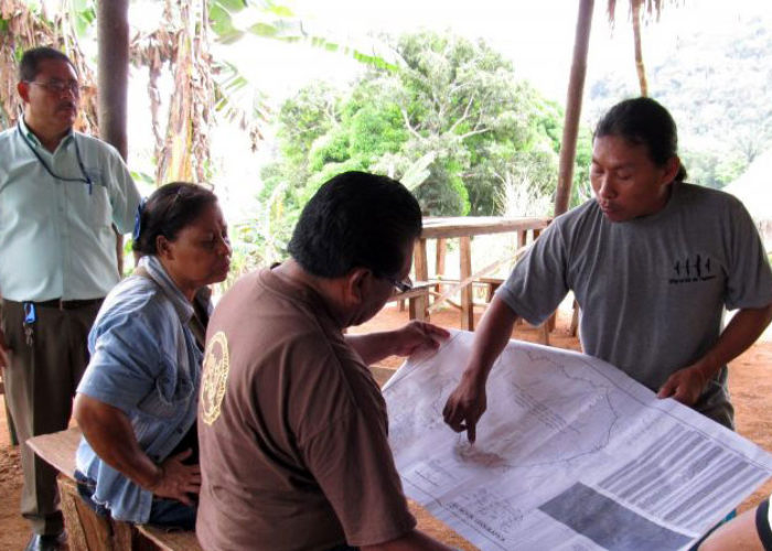 Indigenous community members examine a map of their territory