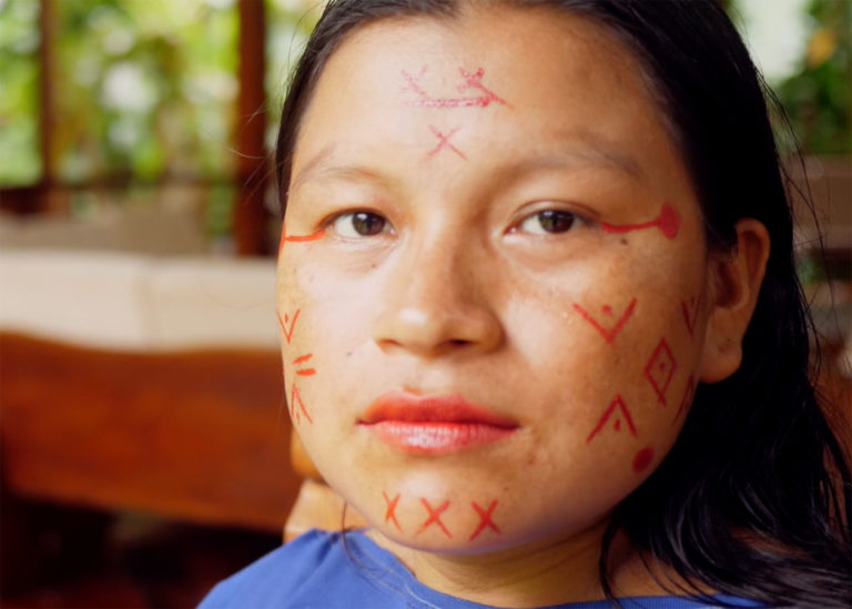 Diana Rios, a young indigenous woman, in traditional red face paint