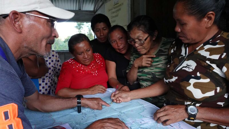 Indigenous people gather around a map of their territories in Guyana.