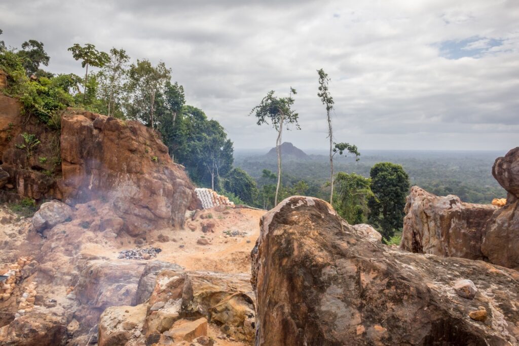 a rocky landscape with trees and a cloudy sky