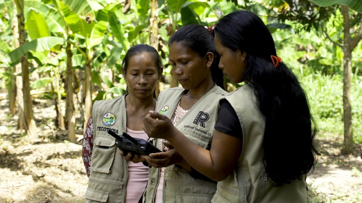 Three Indigenous women using a drone to monitor their rainforest territories